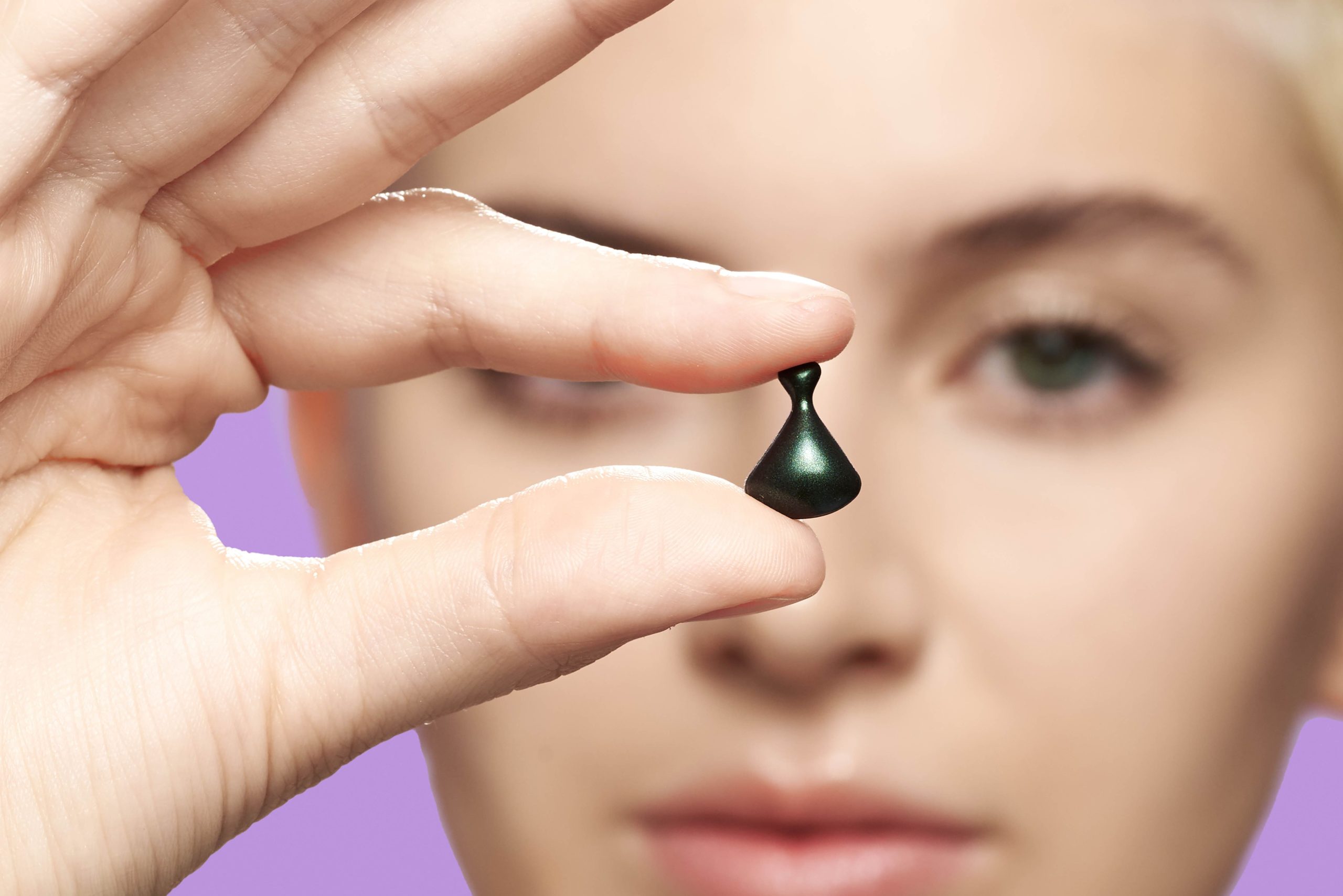 Woman holding up one of the Jade Spectra capsules
